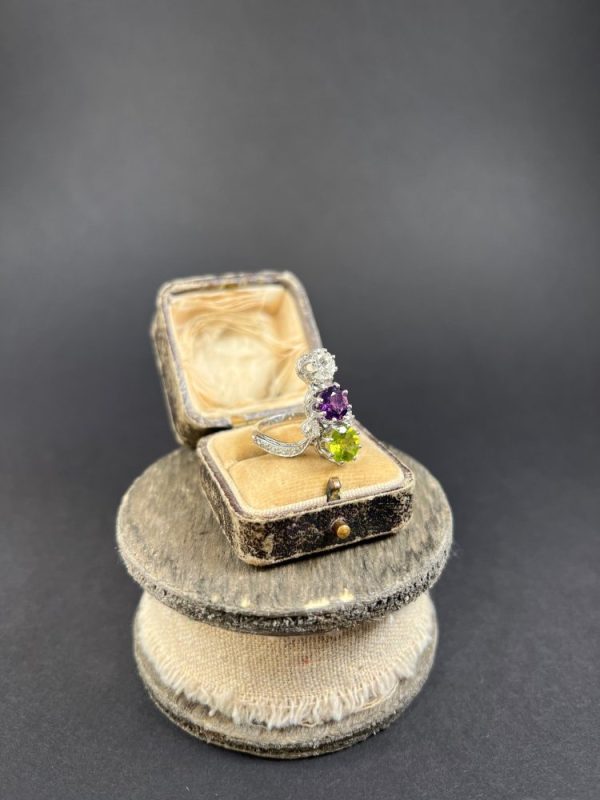Edwardian Antique French Suffragette Amethyst Peridot Diamond Three Stone Ring, graduating trilogy of peridot amethyst and diamond arranged vertically up the finger when worn in 18ct white gold on diamond-set band with French eagles head stamp