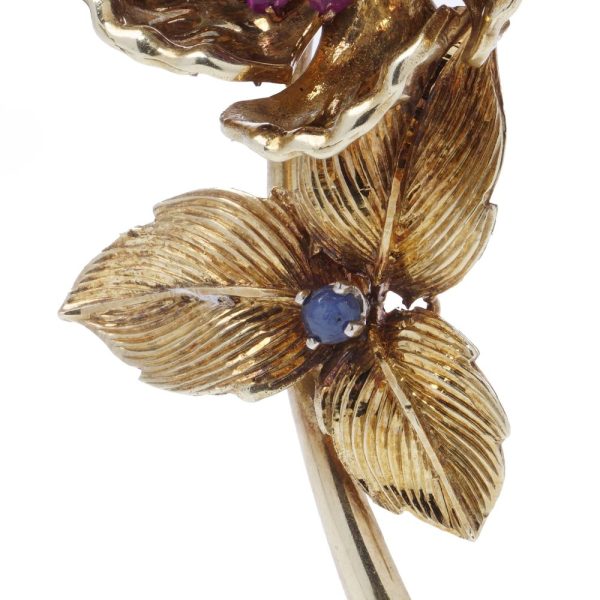 Gold flower brooch with sapphires and rubies.