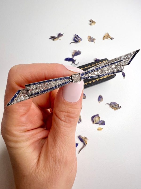 Antique platinum bow brooch, circa 1910, with sapphires and old-cut diamond.