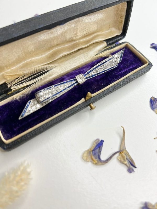 Antique platinum bow brooch, circa 1910, with sapphires and old-cut diamond.