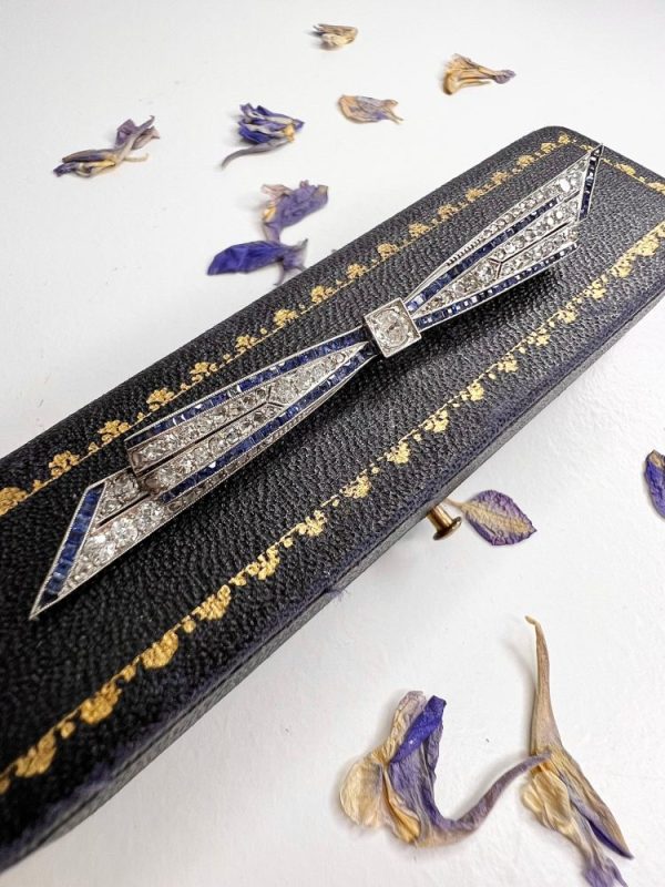 Antique platinum bow brooch, circa 1910, with sapphires and old-cut diamond.