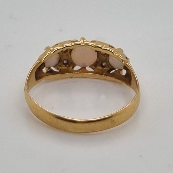 An antique 18ct yellow gold ring featuring three round opal cabochons with four small diamonds set between them in a classic design