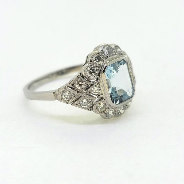 1ct Aquamarine and Diamond Cluster Dress Ring, 1ct emerald-cut aquamarine within decorative 0.60ct diamond set mount in 18ct white gold