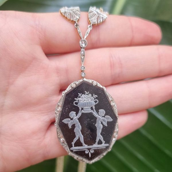 Antique Onyx and Rock Crystal Intaglio Pendant on Seed Pearl Sautoir Necklace, long geometric strung seed pearls suspends oval black onyx and rock crystal intaglio pendant featuring two winged cherubs holding aloft  flowers in an urn