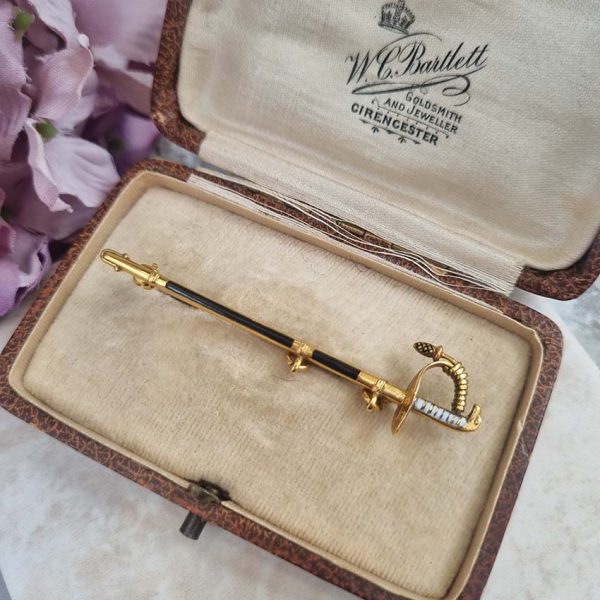 Vintage Gold and Enamel Sword Pin Brooch, yellow gold sword detailed with black enamel along the scabbard sheath and white enamel to the hilt with acorn/pineapple pendant drop
