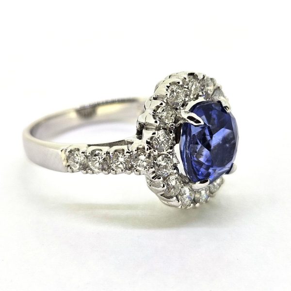 2.96ct Sapphire and Diamond Halo Cluster Engagement Ring in 18ct White Gold, 2.96ct blue sapphire surrounded by fixed halo border of sparkling diamonds with diamond shoulders