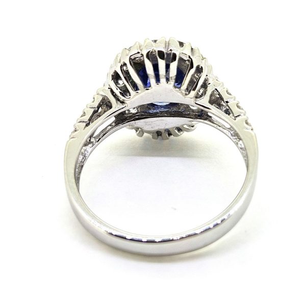 2.96ct Sapphire and Diamond Halo Cluster Engagement Ring in 18ct White Gold, 2.96ct blue sapphire surrounded by fixed halo border of sparkling diamonds with diamond shoulders