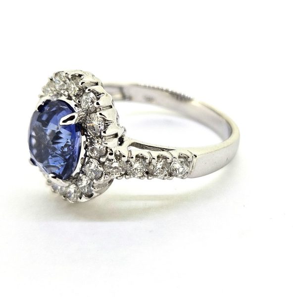 2.96ct Sapphire and Diamond Halo Cluster Engagement Ring in 18ct White Gold, 2.96ct blue sapphire surrounded by fixed halo border of sparkling diamonds with diamond shoulders