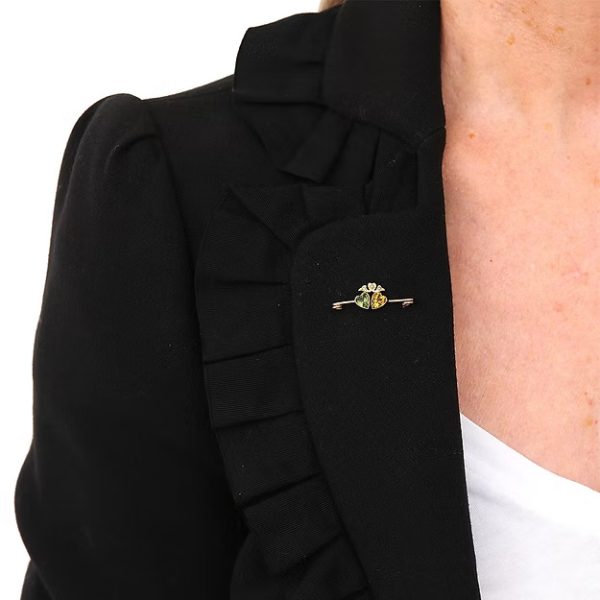 Edwardian 9ct gold brooch featuring twin hearts set with peridot and citrine, topped with a floral crown motif adorned with split pearls, circa 1910