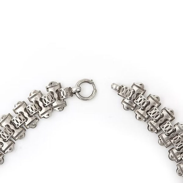 Victorian silver collar necklace featuring engraved flat links, foliate connectors, and heart-shaped details, circa 1880.
