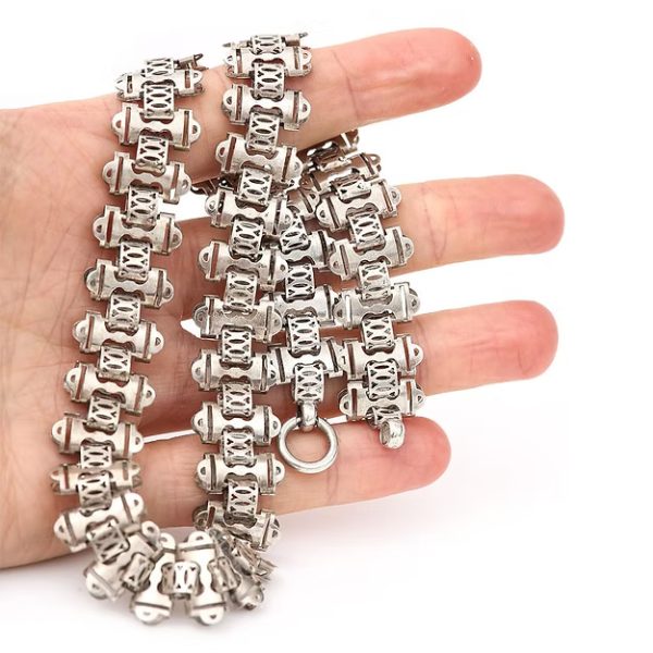 Victorian silver collar necklace featuring engraved flat links, foliate connectors, and heart-shaped details, circa 1880.