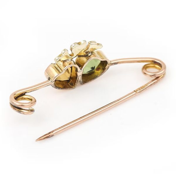 Edwardian 9ct gold brooch featuring twin hearts set with peridot and citrine, topped with a floral crown motif adorned with split pearls, circa 1910