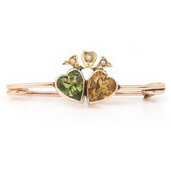 Edwardian 9ct gold brooch featuring twin hearts set with peridot and citrine, topped with a floral crown motif adorned with split pearls, circa 1910