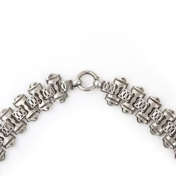 Victorian silver collar necklace featuring engraved flat links, foliate connectors, and heart-shaped details, circa 1880.