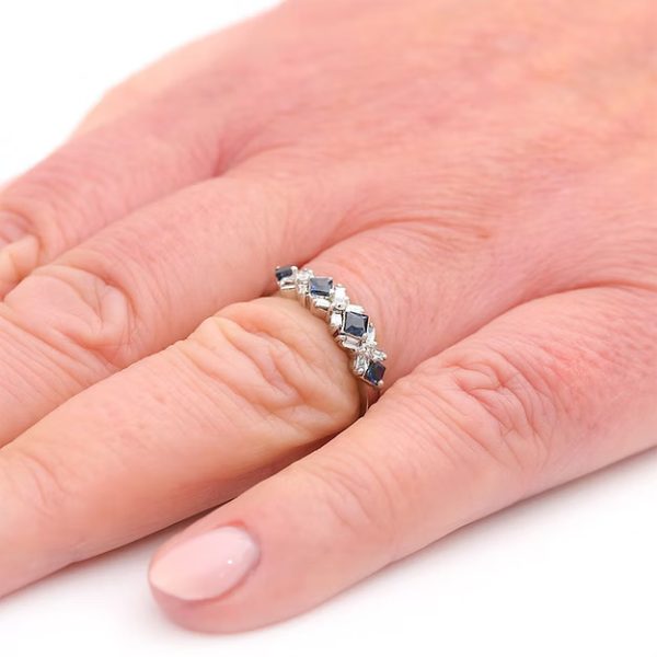 Contemporary 18ct white gold half eternity ring with square-cut blue sapphires and baguette and brilliant-cut diamonds in a geometric design.