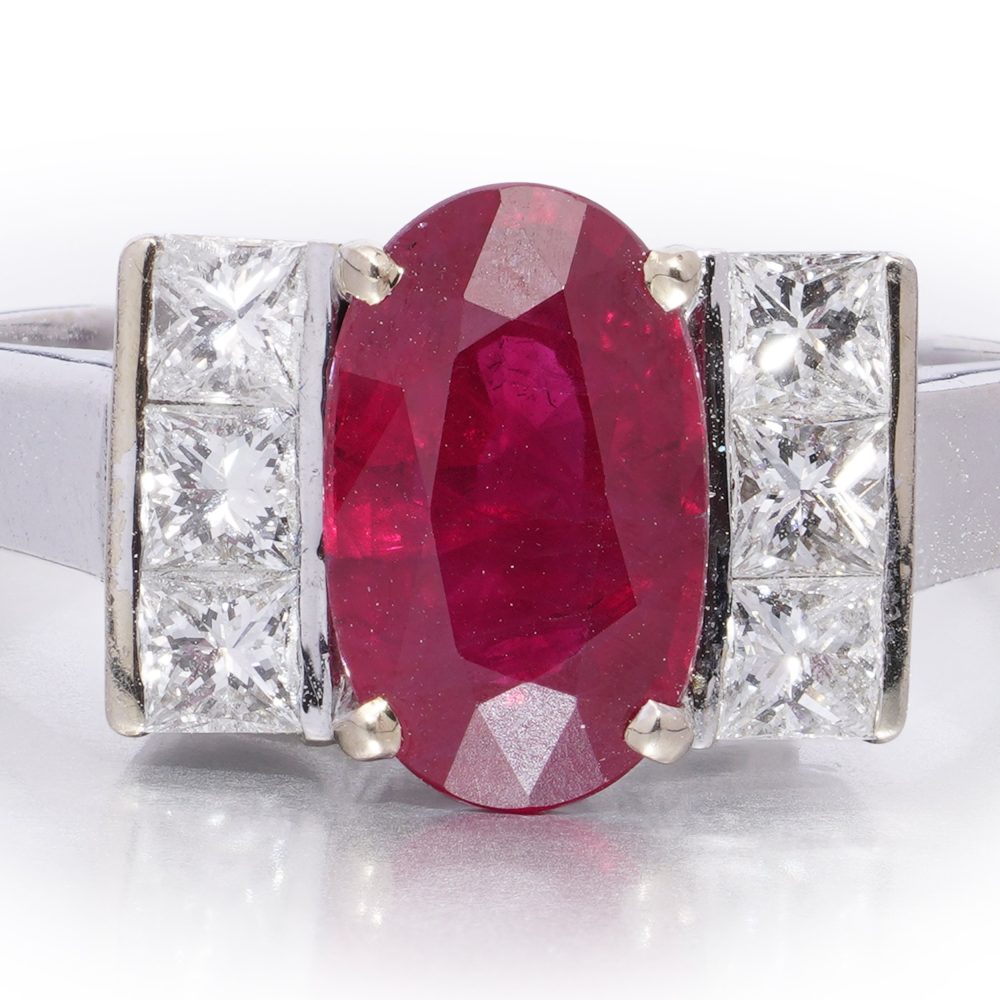 2.15ct Oval Ruby and Princess Cut Diamond Engagement Ring, vibrant oval mixed-cut natural ruby flanked by a row of vertically set square princess-cut diamonds to each side in 18ct white gold
