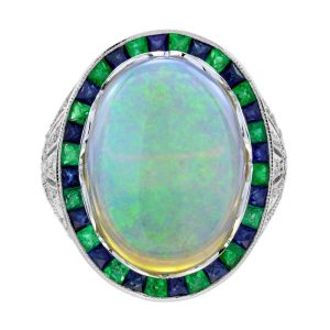 8.73ct Opal Emerald Sapphire Cluster Cocktail Ring, central luminous opal encircled by vivid French-cut emeralds alternated with blue sapphires in 18ct white gold with diamond shoulders