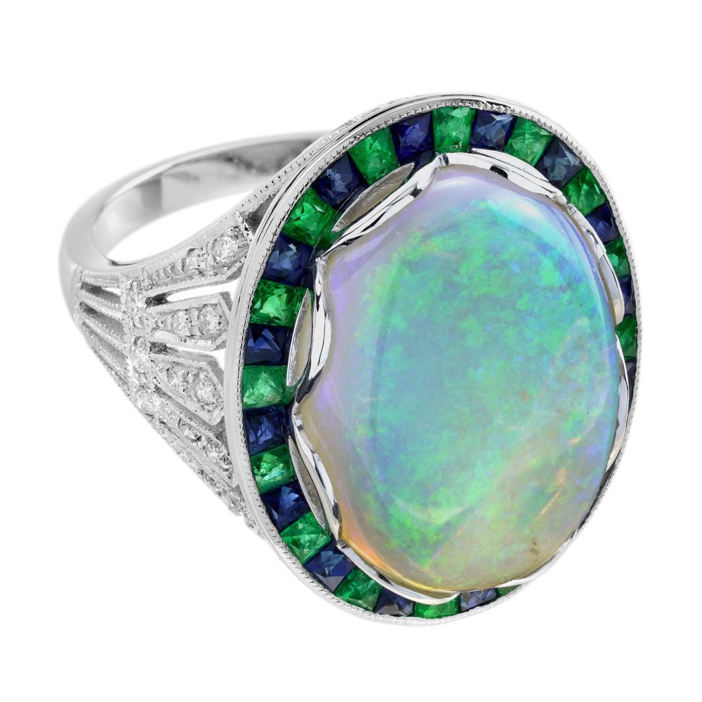 8.73ct Opal Emerald Sapphire Cluster Cocktail Ring, central luminous opal encircled by vivid French-cut emeralds alternated with blue sapphires in 18ct white gold with diamond shoulders