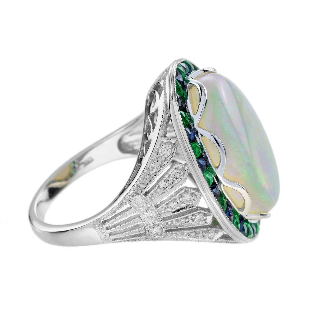 8.73ct Opal Emerald Sapphire Cluster Cocktail Ring, central luminous opal encircled by vivid French-cut emeralds alternated with blue sapphires in 18ct white gold with diamond shoulders