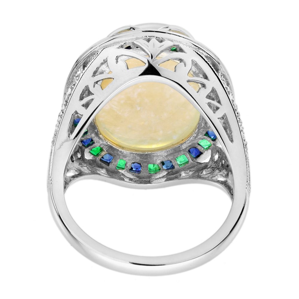 8.73ct Opal Emerald Sapphire Cluster Cocktail Ring, central luminous opal encircled by vivid French-cut emeralds alternated with blue sapphires in 18ct white gold with diamond shoulders