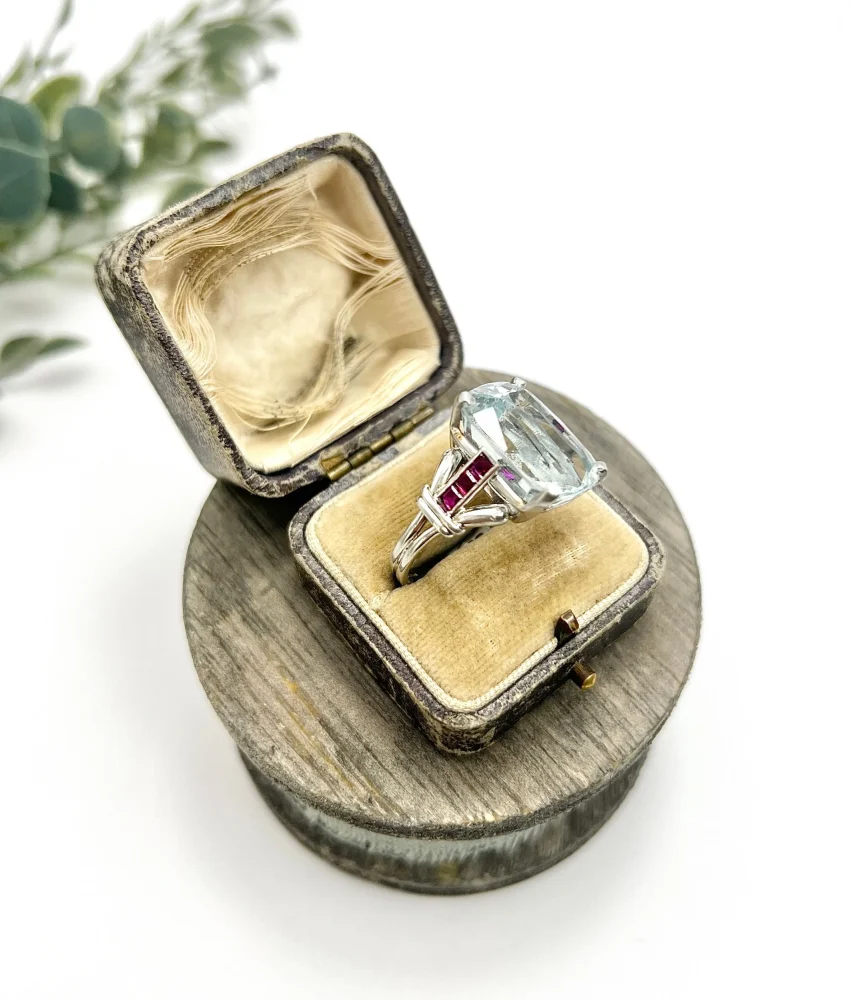 Vintage Cushion Cut Aquamarine Cocktail Ring with Ruby Shoulders in Platinum, 12ct cushion-cut aquamarine on reeded platinum band set with calibre red rubies. Circa 1960s