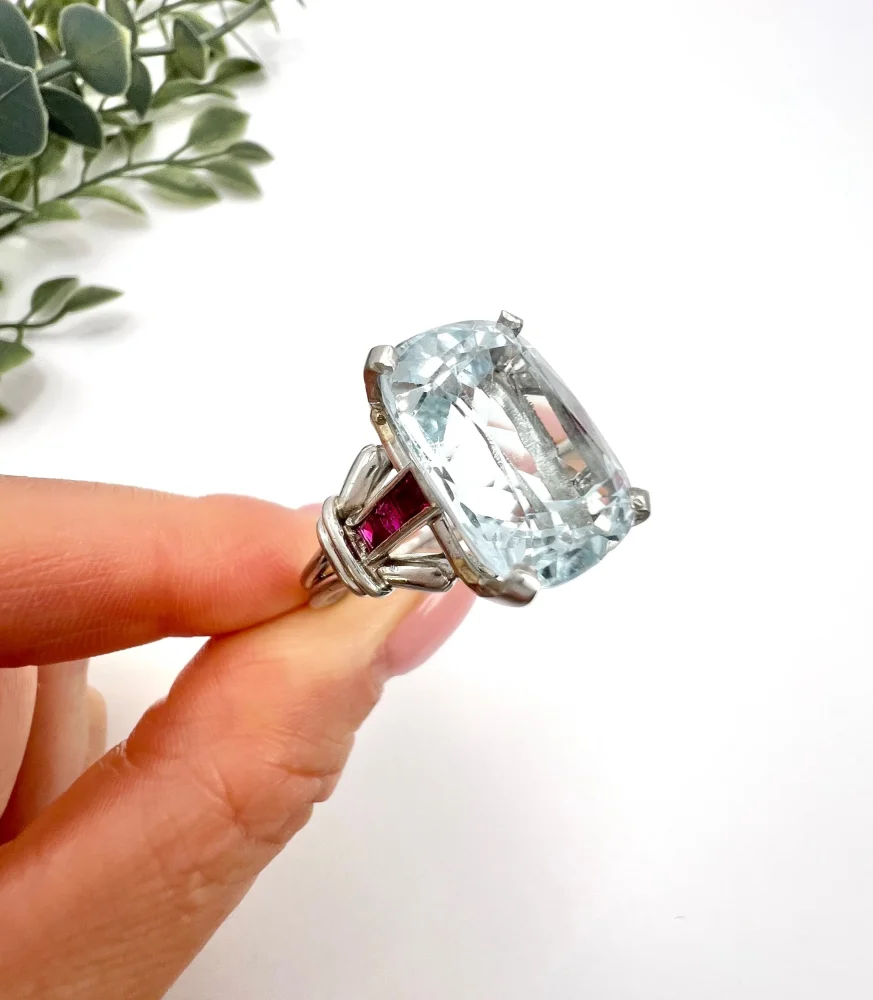Vintage Cushion Cut Aquamarine Cocktail Ring with Ruby Shoulders in Platinum, 12ct cushion-cut aquamarine on reeded platinum band set with calibre red rubies. Circa 1960s
