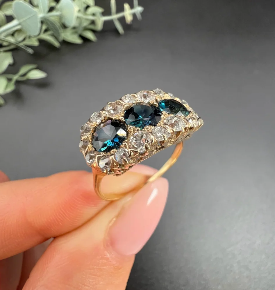 Edwardian Antique Sapphire and Diamond Triple Cluster Ring, trilogy sapphires framed by halos of sparkling old-cut diamonds in 18ct rose gold. Circa 1900