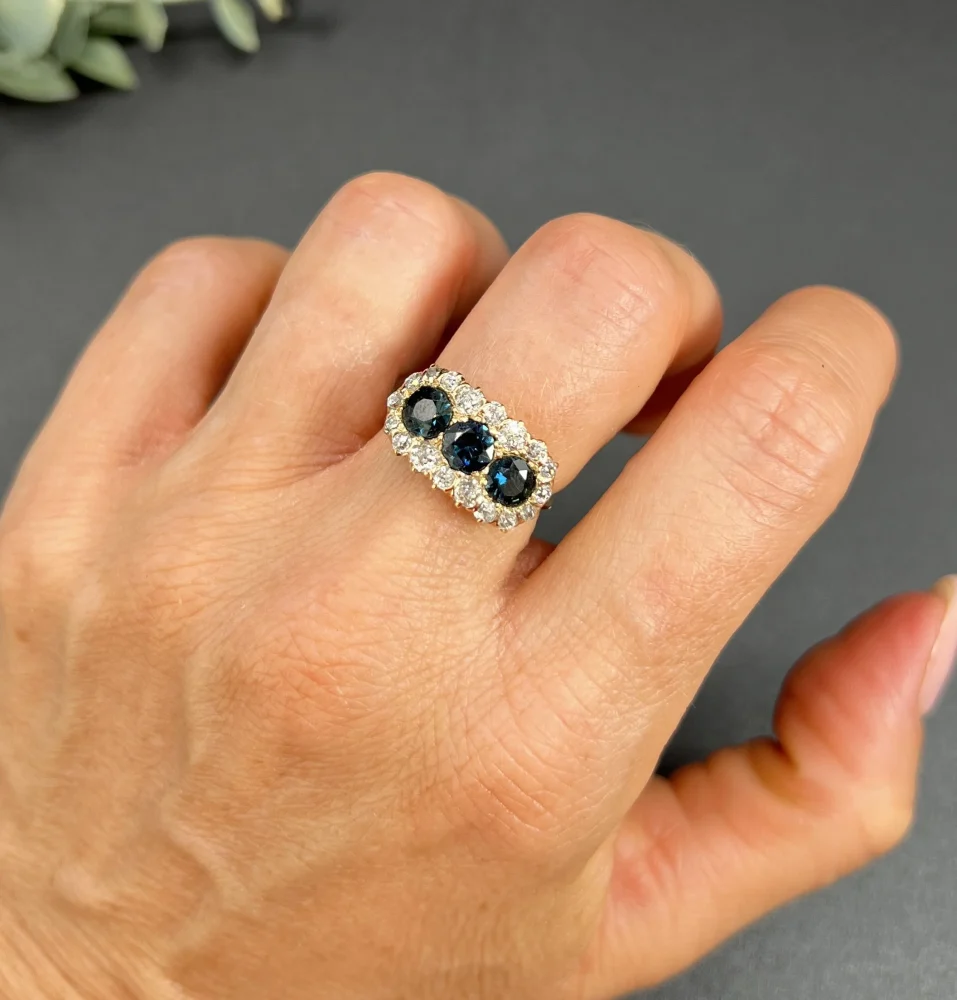 Edwardian Antique Sapphire and Diamond Triple Cluster Ring, trilogy sapphires framed by halos of sparkling old-cut diamonds in 18ct rose gold. Circa 1900
