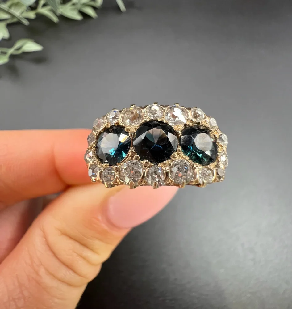 Edwardian Antique Sapphire and Diamond Triple Cluster Ring, trilogy sapphires framed by halos of sparkling old-cut diamonds in 18ct rose gold. Circa 1900