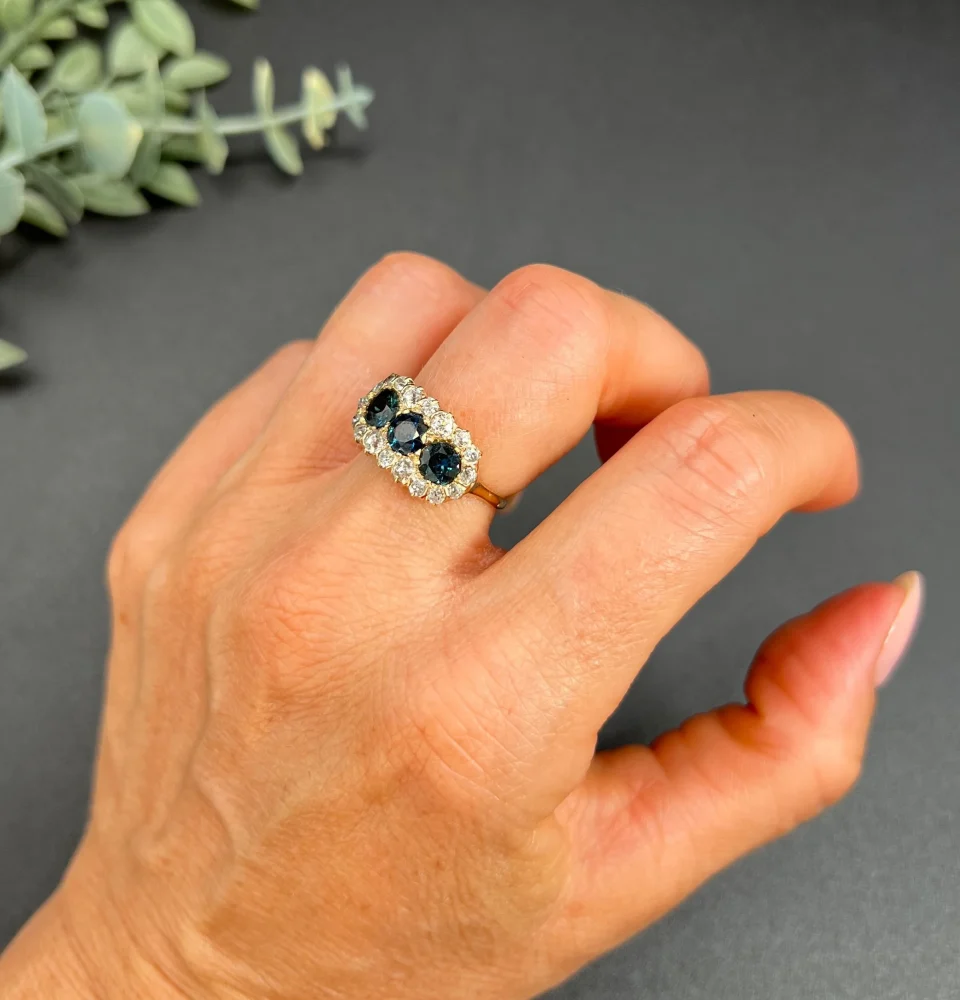 Edwardian Antique Sapphire and Diamond Triple Cluster Ring, trilogy sapphires framed by halos of sparkling old-cut diamonds in 18ct rose gold. Circa 1900