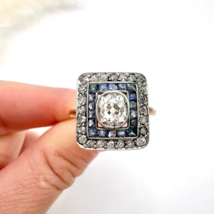 Edwardian Antique Sapphire and Diamond Square Cluster Target Ring, 1ct cushion-cut diamond surrounded by halo of calibre blue sapphires within outer border of diamonds in 18ct gold. Circa 1910