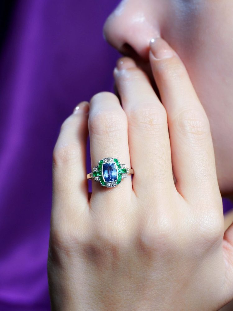 1.60ct Ceylon Sapphire Emerald and Diamond Engagement Ring, cushion-shape certified Ceylon sapphire flanked by vibrant green emeralds accented with diamonds in geometric detailing in 18ct white gold