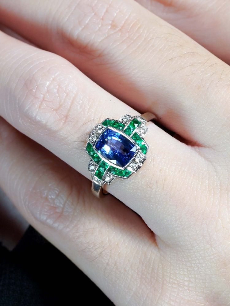 1.60ct Ceylon Sapphire Emerald and Diamond Engagement Ring, cushion-shape certified Ceylon sapphire flanked by vibrant green emeralds accented with diamonds in geometric detailing in 18ct white gold