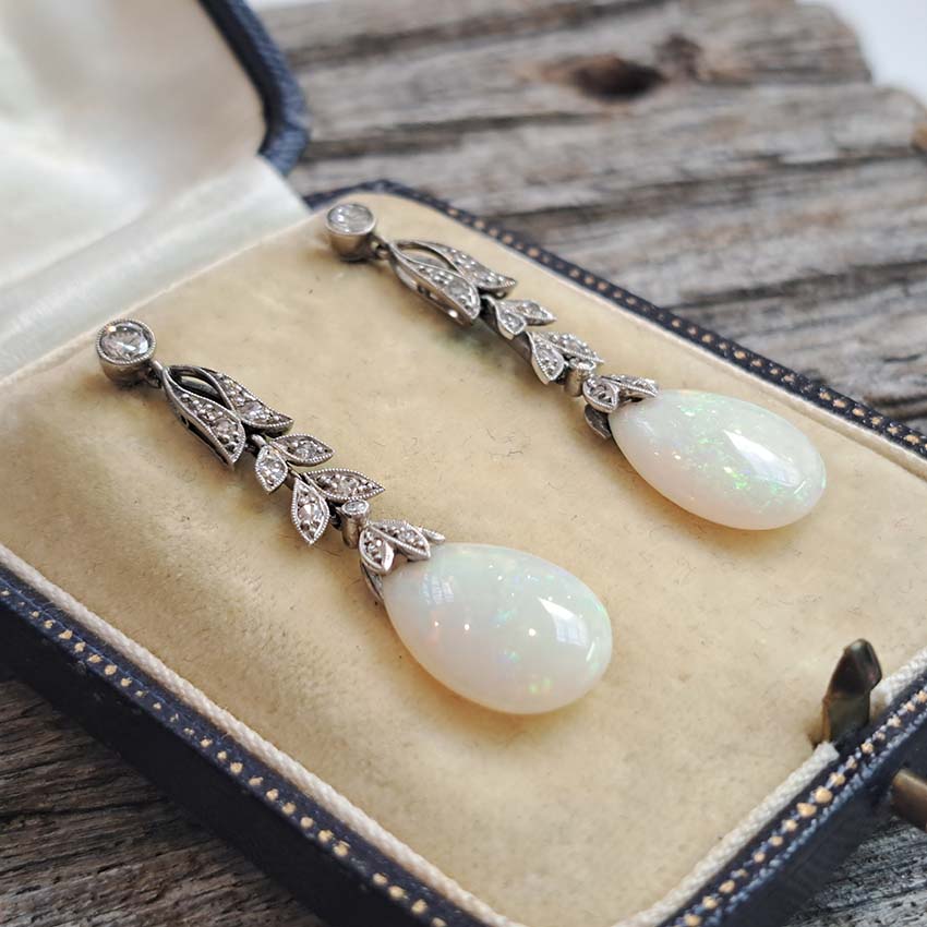Edwardian Antique Opal and Diamond Drop Earrings, Diamond tops suspend floral diamond leaf designs with trefoil diamond caps holding pear drop opals