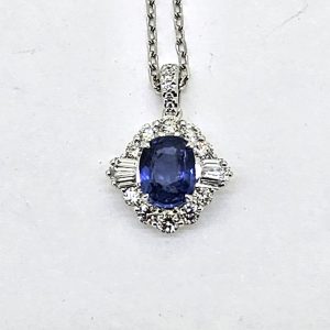 Modern 1.40ct Oval Sapphire and Diamond Cluster Pendant, 1.40ct oval blue sapphire surrounded by brilliant and baguette diamonds on diamond-set bail in 18ct white gold